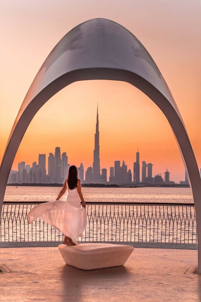 Photo of a girl in front of the Dubai Towers at sunset