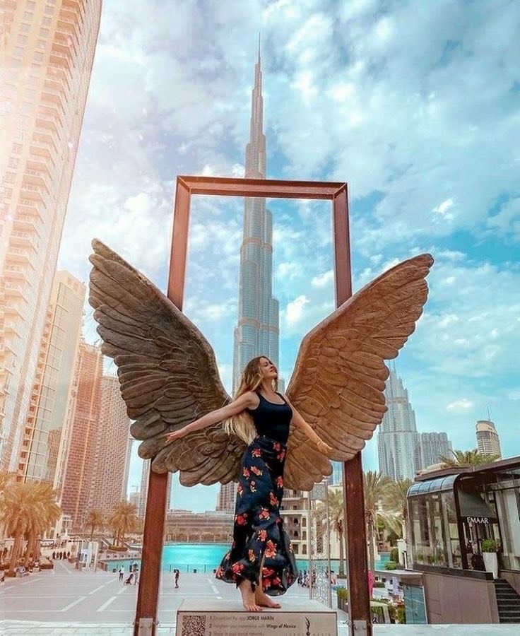 a girl with the wings of an angel in front of the Burj Khalifa