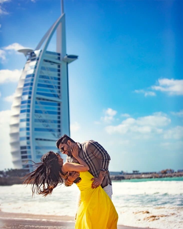 Photo of a couple on the beach in front of the Dubai Tower
